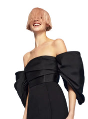 Woman wearing a black off-shoulder dress against a blue sky