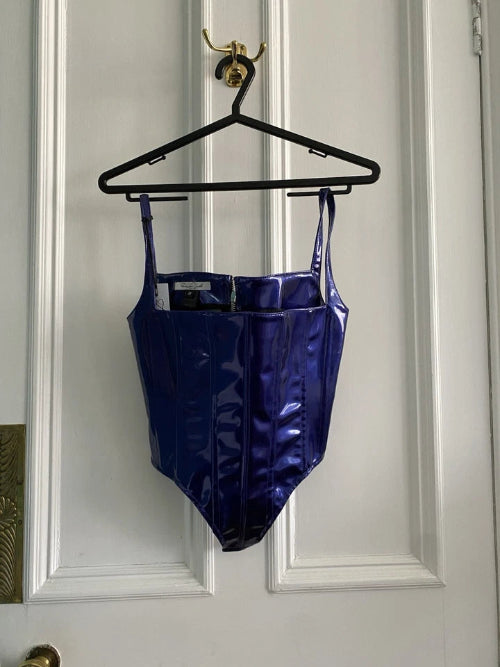 Blue swimsuit hanging on a black hanger against a white door.