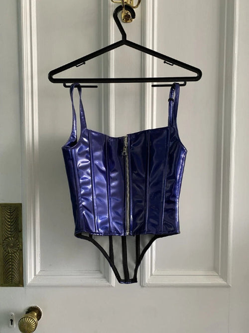 Blue metallic corset top on a hanger against a white paneled door.