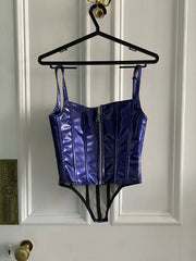 Blue metallic corset top on a hanger against a white paneled door.