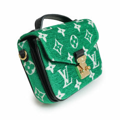 Green handbag with white monogram pattern on a white background