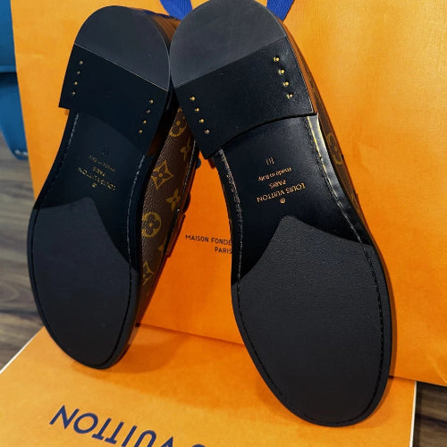 Black shoes with a patterned sole on an orange surface