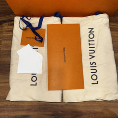 Louis Vuitton packaging with orange card and white paper on a wooden surface