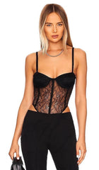 Woman wearing a black lace bodysuit against a white background