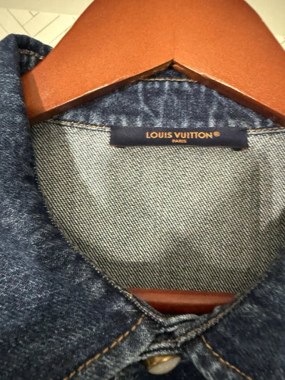 Close-up of a Louis Vuitton label on denim fabric with brown leather trim.