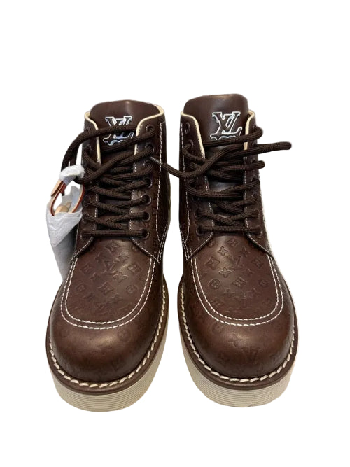 A pair of brown leather lace-up boots with white rubber soles, shown against a neutral gray background.