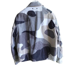 Camouflage-patterned jacket hanging on a stand with a blurred outdoor background
