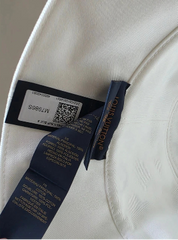 Close-up of a label on a white garment with text and a barcode.