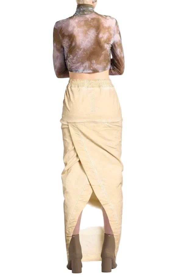 A vintage-style sculpture of a seated female figure wearing a beige sarong and brown leather sandals, shown against a plain white background.