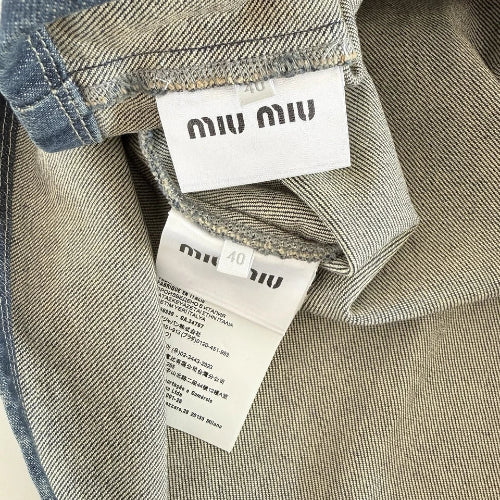 Two clothing tags with 'miu miu' branding on a gray background