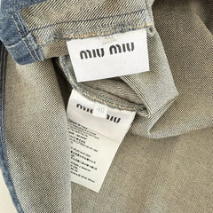 Two clothing tags with 'miu miu' branding on a gray background