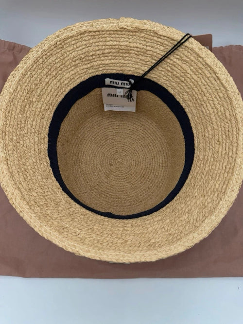 Beige straw hat with black band on a brown surface