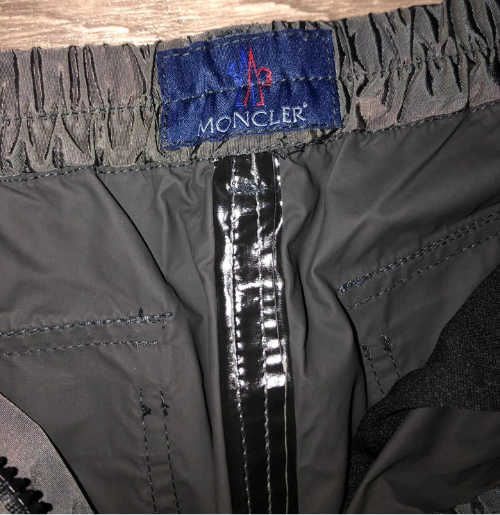 Moncler label on a gray jacket with a wooden background