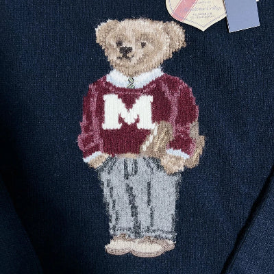 Navy sweater with embroidered teddy bear wearing a red sweater with a white 'M' on a navy background.