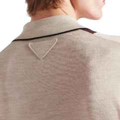Close-up of a beige sweater with a triangle pattern on the collar against a neutral background