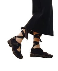 Black strappy sandals worn with a black skirt against a blurred outdoor background