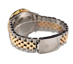 Close-up of a silver and gold watch band on a white surface with a blurred background