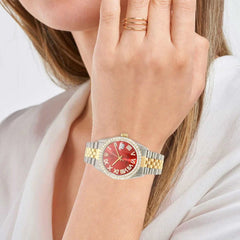 Close-up of a hand wearing a gold ring and pink watch on a white background