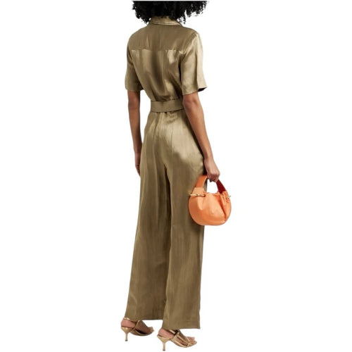 Woman wearing a gold jumpsuit holding an orange handbag on a white background