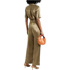 Woman wearing a gold jumpsuit holding an orange handbag on a white background
