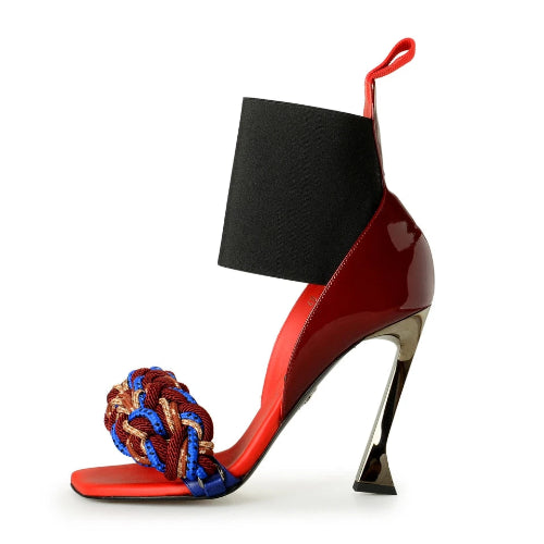 Red high-heeled shoe with a colorful sole and a black box on a white background