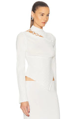 Woman wearing a white long-sleeve dress with a high neckline.