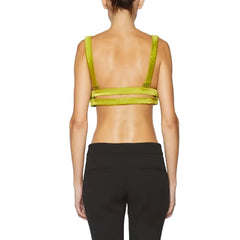 Person wearing a green sports bra and black leggings on a plain background
