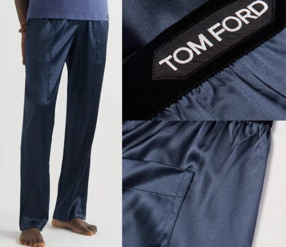 A close-up of dark navy blue trousers with a black fabric label showing the white TOM FORD logo.