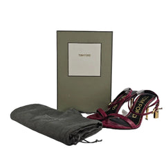 Folded gray blanket with a patterned scarf on top, next to a green box with a brand logo.