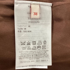 A close-up of a white laundry care label attached to a brown garment, showing the brand name '38' and washing instructions.