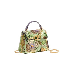 A structured green handbag with an intricate floral embroidery and beadwork pattern in gold, purple, and green, featuring a dark purple top handle, gold-tone hardware, and a gold chain shoulder strap, set against a plain white background.