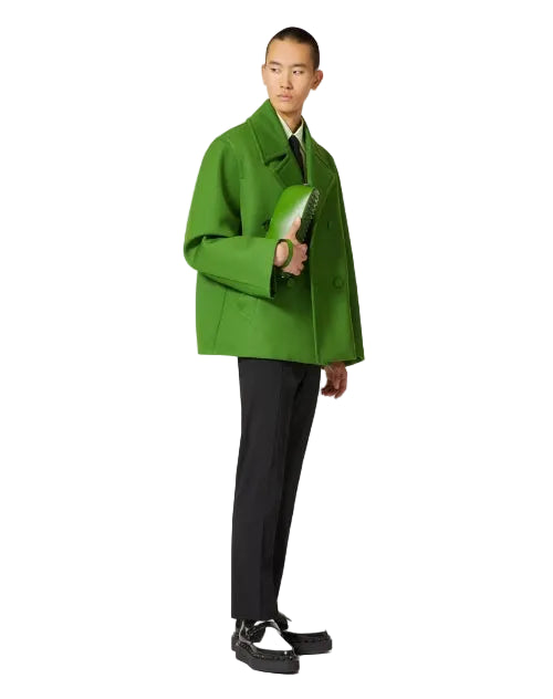 Person wearing a bright green coat and black pants on a white background