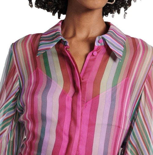 A close-up of a woman wearing a long-sleeve button-up shirt with vertical pink, green, purple, and white stripes.