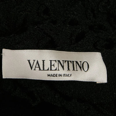 A close-up of a black textured garment with a white Valentino brand label reading 'VALENTINO MADE IN ITALY'.