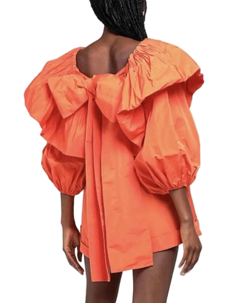 Orange dress with puff sleeves and a bow detail on a white background