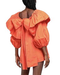 Orange dress with puff sleeves and a bow detail on a white background