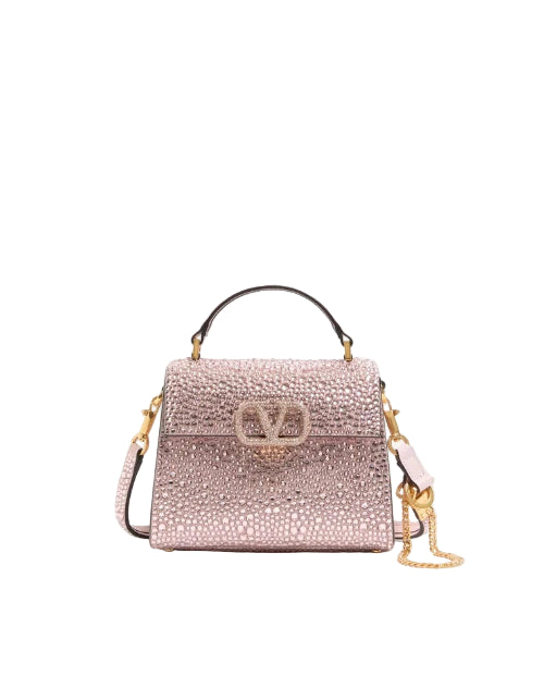 Pink handbag with gold chain on a light pink background