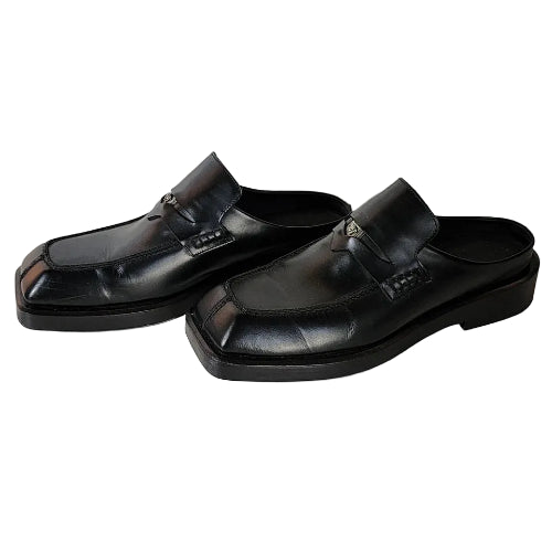 Pair of black loafers on a light wooden floor.