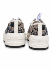 A pair of low-top sneakers shown from the back, featuring a black and white abstract patterned upper with white midsoles and white laces.