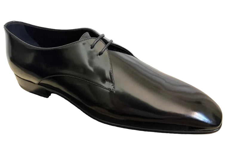 Shiny black dress shoe on a dark surface with a light background