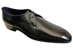 Shiny black dress shoe on a dark surface with a light background