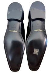Black dress shoes with 'Saint Laurent' branding on a light gray surface.