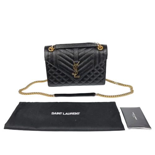 Black quilted handbag with gold chain and Saint Laurent pouch on a white background