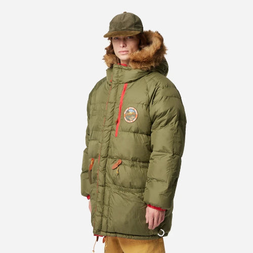 Person wearing a green winter coat with fur hood on a white background