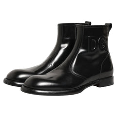 A pair of glossy black ankle boots with decorative side cutouts, shown against a plain white background.
