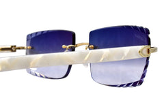 Sunglasses with blue lenses and gold frames on a reflective surface