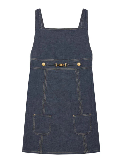Denim pinafore dress with gold hardware on a white background