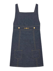Denim pinafore dress with gold hardware on a white background