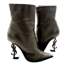 Pair of black high-heeled boots with unique heel designs on a white background