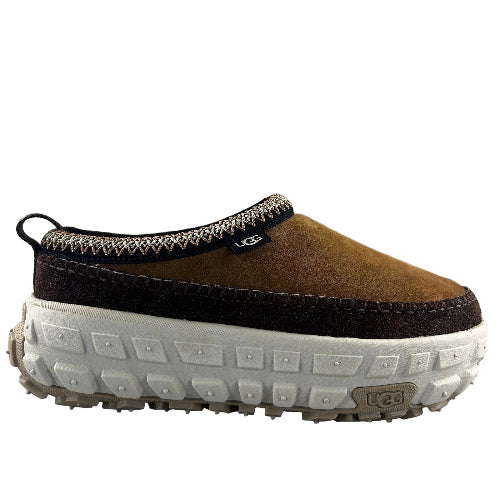 Brown UGG slip-on shoe with white sole on a gray background